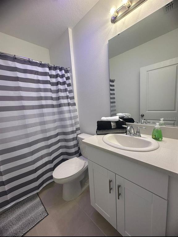 A bathroom features a white vanity, a striped shower curtain, and a wall-mounted mirror — 3921 SOUTHERN VISTA LOOP, ST CLOUD, FL