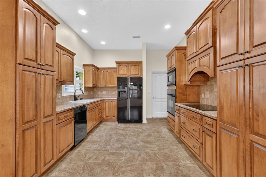 A kitchen with wood cabinets, granite countertops, stainless steel appliances, and tile flooring — 1557 OAK FOREST DRIVE, THE VILLAGES, FL