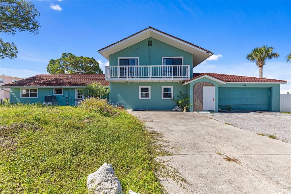 A two-story teal house with a tiled roof, balcony, and concrete driveway — 3016 SUNSET VISTA DRIVE, SPRING HILL, FL