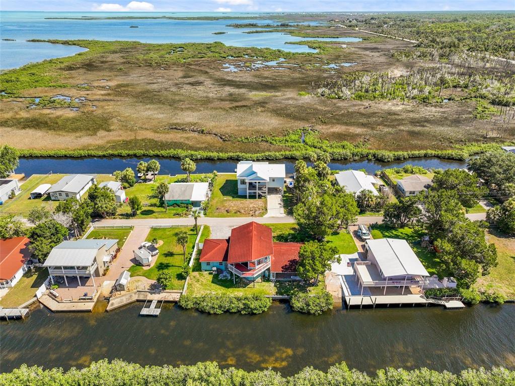 An aerial view shows several waterfront houses with docks along a canal near marshland — 3016 SUNSET VISTA DRIVE, SPRING HILL, FL