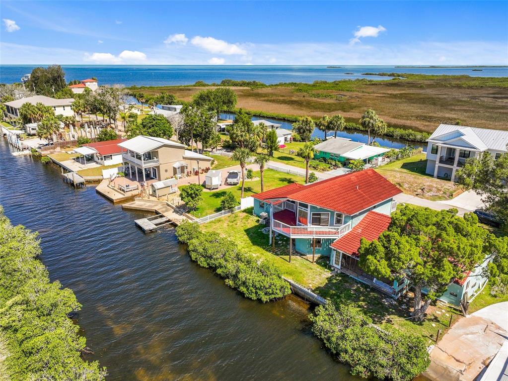 An aerial view shows waterfront houses with red roofs along a canal near the ocean — 3016 SUNSET VISTA DRIVE, SPRING HILL, FL