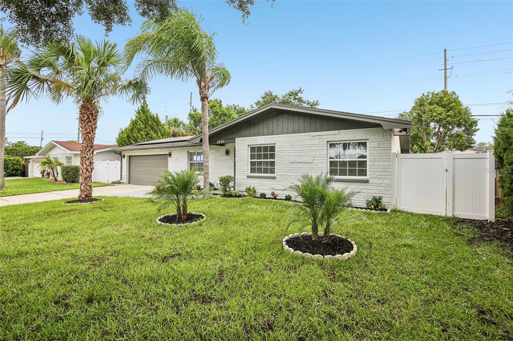 A single-story house with a white brick exterior, gray trim, and a front lawn with palms — 2230 ALBRIGHT DRIVE, CLEARWATER, FL