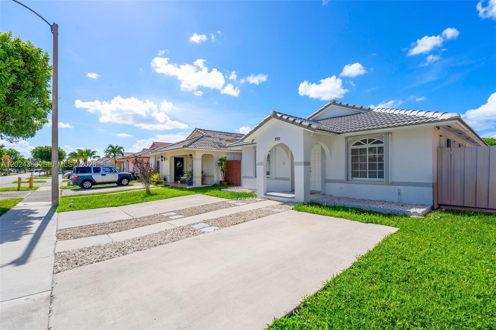 A single-story house with a white stucco facade, tiled roof, and a concrete driveway — 9703 NW 127th St, Hialeah Gardens FL 33018, HIALEAH GARDENS, FL