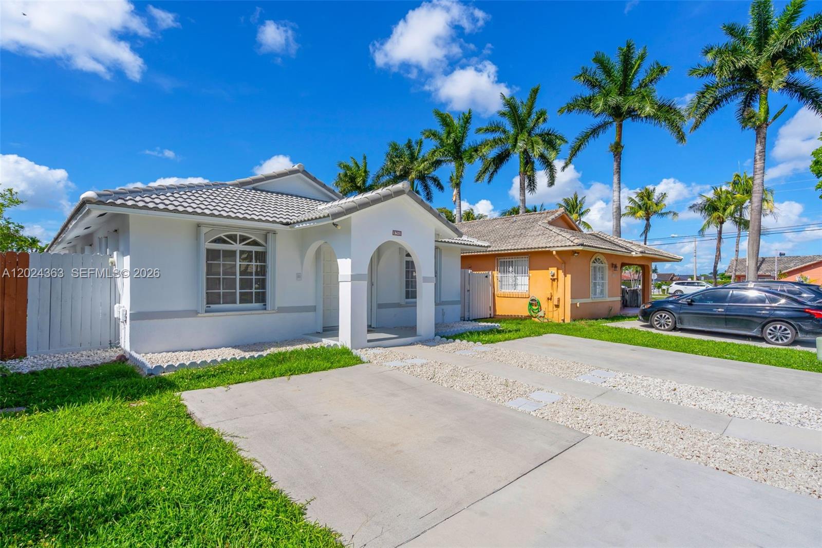 A white house with a tiled roof and a concrete driveway sits next to an orange house — 9703 NW 127th St, Hialeah Gardens FL 33018, HIALEAH GARDENS, FL