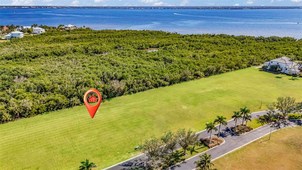 An aerial view shows a large, grassy lot with a red pin marker near trees — 4661 GRASSY POINT BOULEVARD, PORT CHARLOTTE, FL