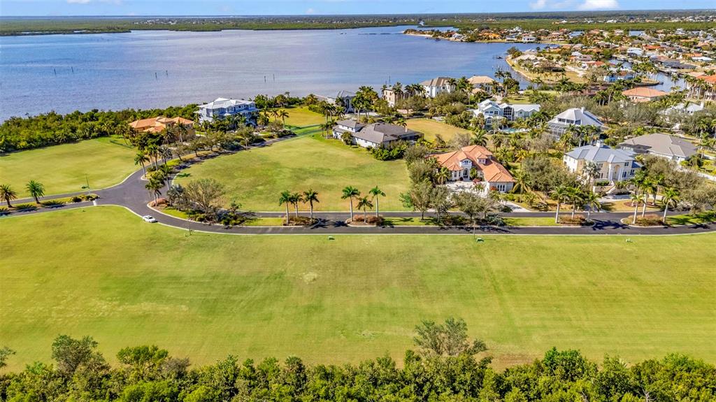 An aerial view shows a large grassy field with a curved road and several houses — 4661 GRASSY POINT BOULEVARD, PORT CHARLOTTE, FL