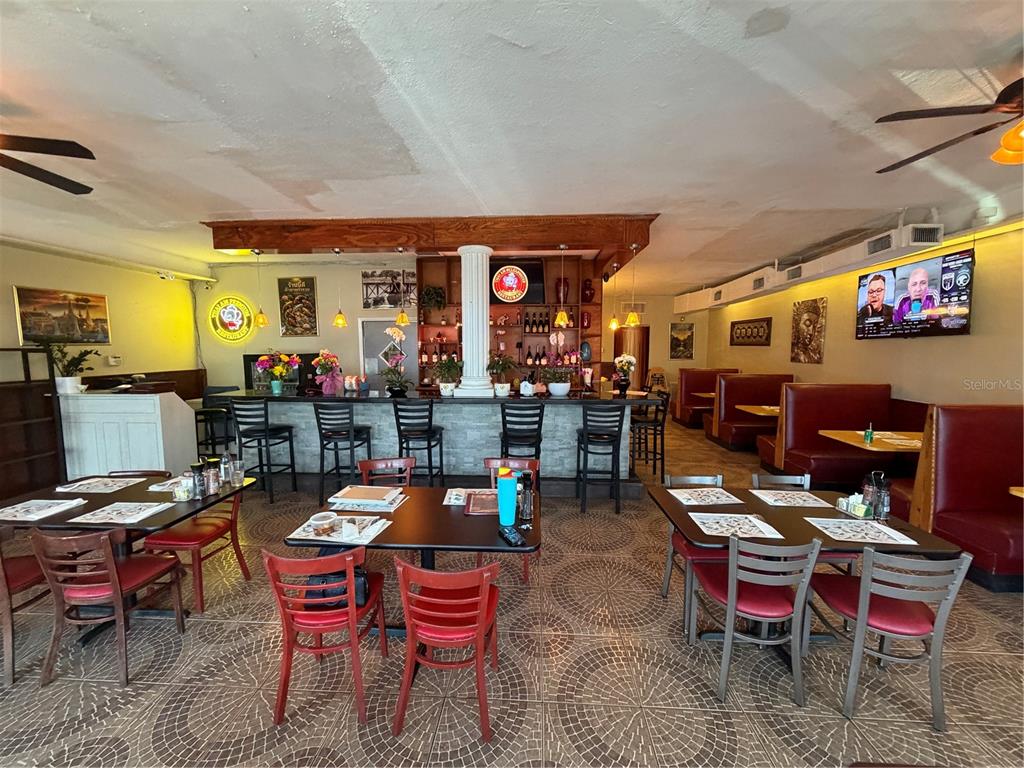 A restaurant interior features a bar with stools, dining tables with red chairs, and booths — 1840 DREW STREET, CLEARWATER, FL
