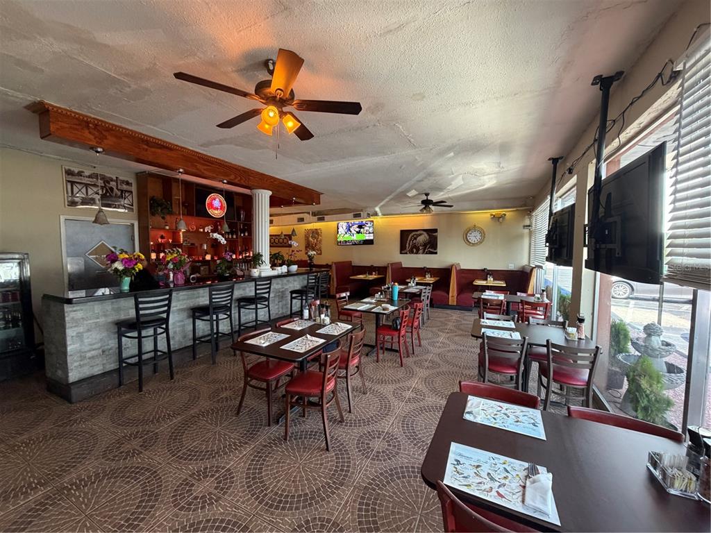 A restaurant interior features a bar, dining tables with chairs, tiled floors, and ceiling fans — 1840 DREW STREET, CLEARWATER, FL