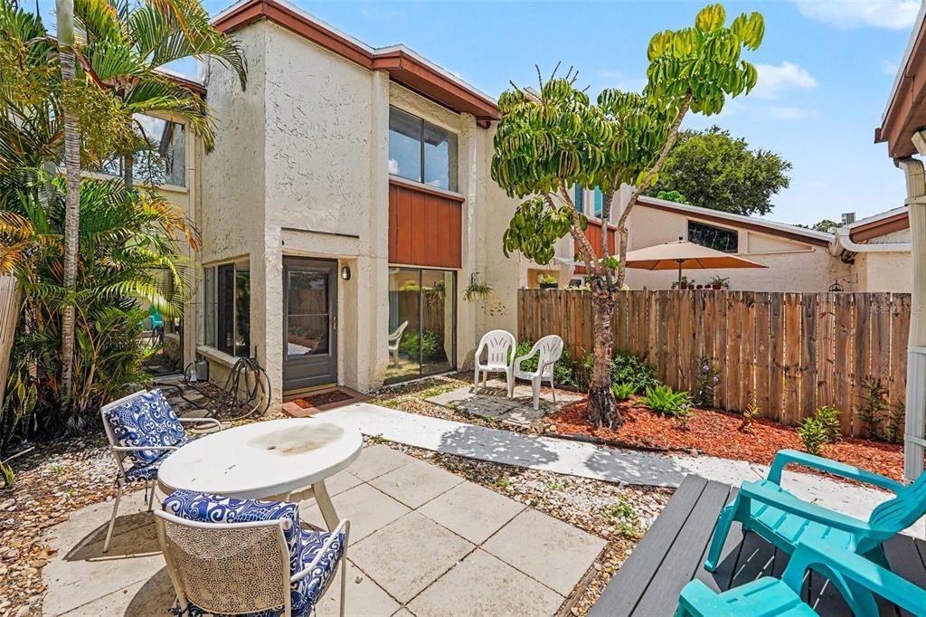 A two-story townhouse exterior features a front entrance, sliding glass doors, and a small patio — 2095 SUNSET POINT ROAD UNIT 1904, CLEARWATER, FL