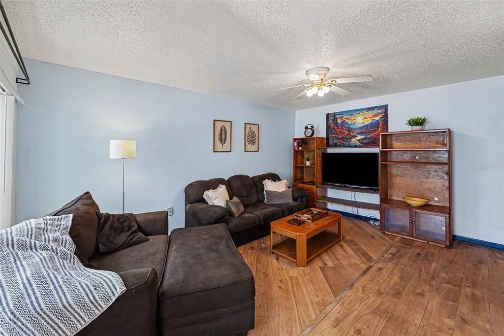A view from a kitchen counter looking into a living room with wood-look flooring — 2095 SUNSET POINT ROAD UNIT 1904, CLEARWATER, FL
