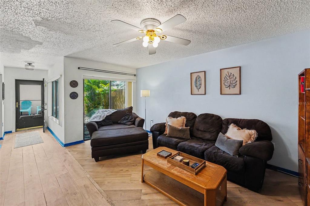 A living room features brown furniture, a wooden entertainment center, and wood-look tile flooring — 2095 SUNSET POINT ROAD UNIT 1904, CLEARWATER, FL