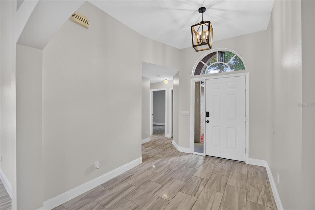 A bright entryway features light-colored walls, wood-look tile flooring, and a modern lantern pendant light — 1434 HATCHER LOOP DRIVE, BRANDON, FL