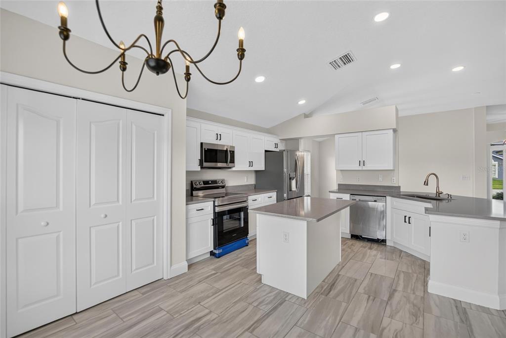 A kitchen with white cabinets, stainless steel appliances, a center island, and wood-look tile flooring — 1434 HATCHER LOOP DRIVE, BRANDON, FL