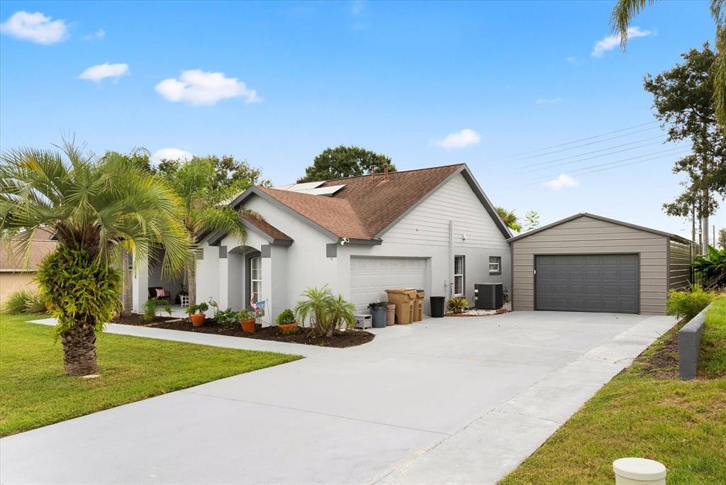 A light-colored house with a brown roof and a detached metal garage — 12724 SCOTTISH PINE LANE, CLERMONT, FL