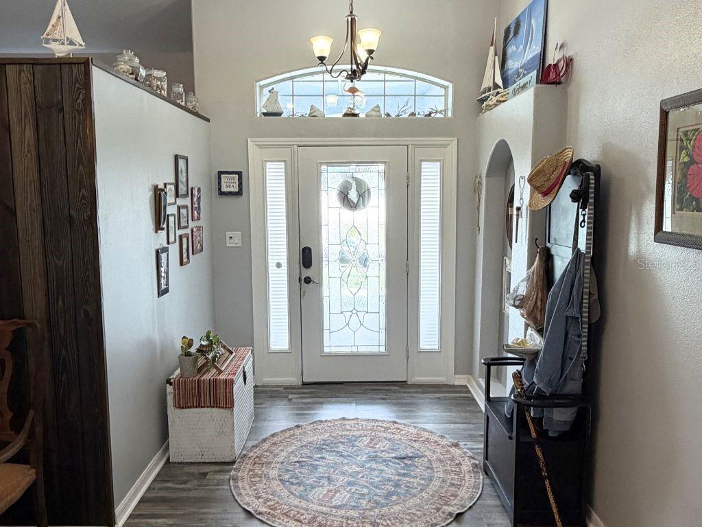 An entryway features a white front door with sidelights, a round rug, and coastal decor — 12724 SCOTTISH PINE LANE, CLERMONT, FL