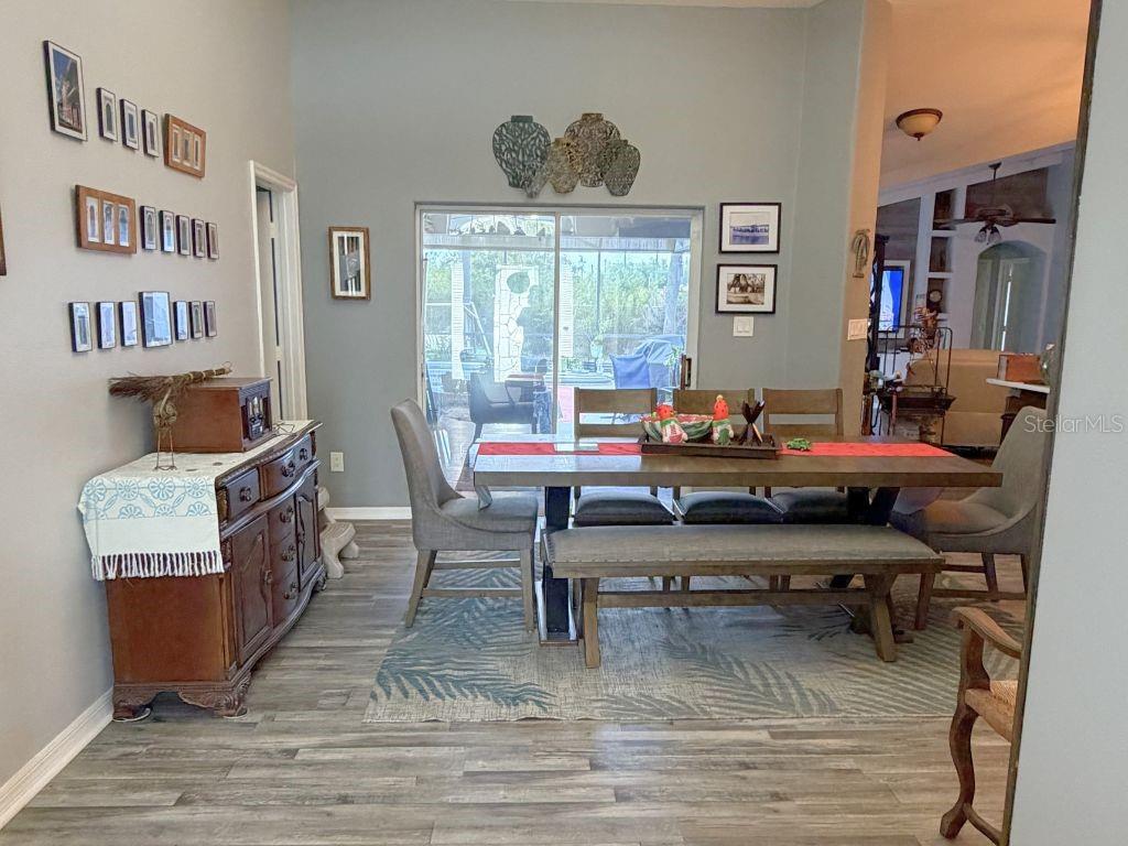 A dining room features a wooden table with a bench, chairs, and a side cabinet — 12724 SCOTTISH PINE LANE, CLERMONT, FL