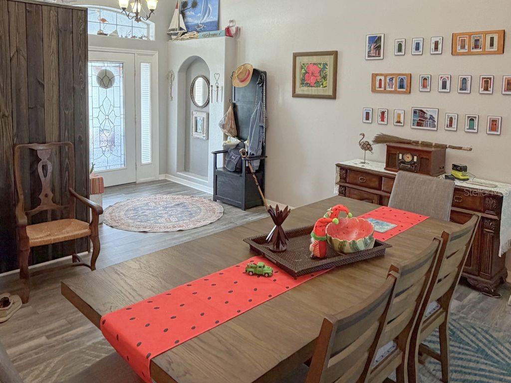 A dining room with a wooden table, chairs, and a gallery wall near an entryway — 12724 SCOTTISH PINE LANE, CLERMONT, FL