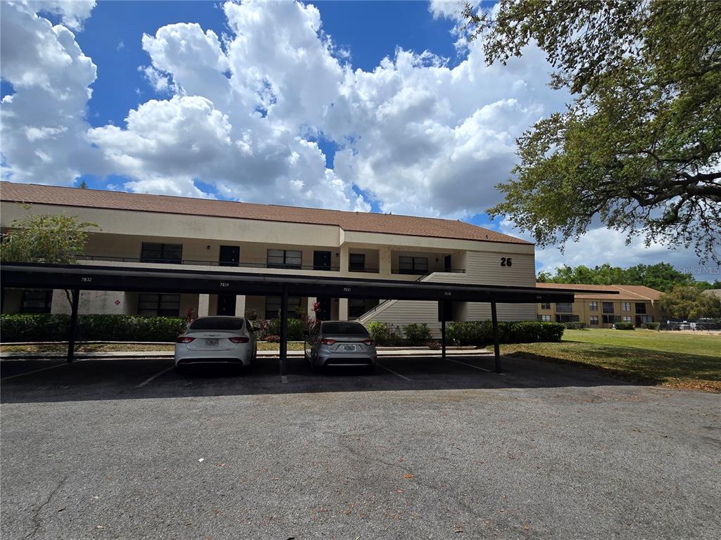 A two-story apartment building with a covered parking structure in the foreground — 7838 NIAGARA AVENUE UNIT 305, TAMPA, FL