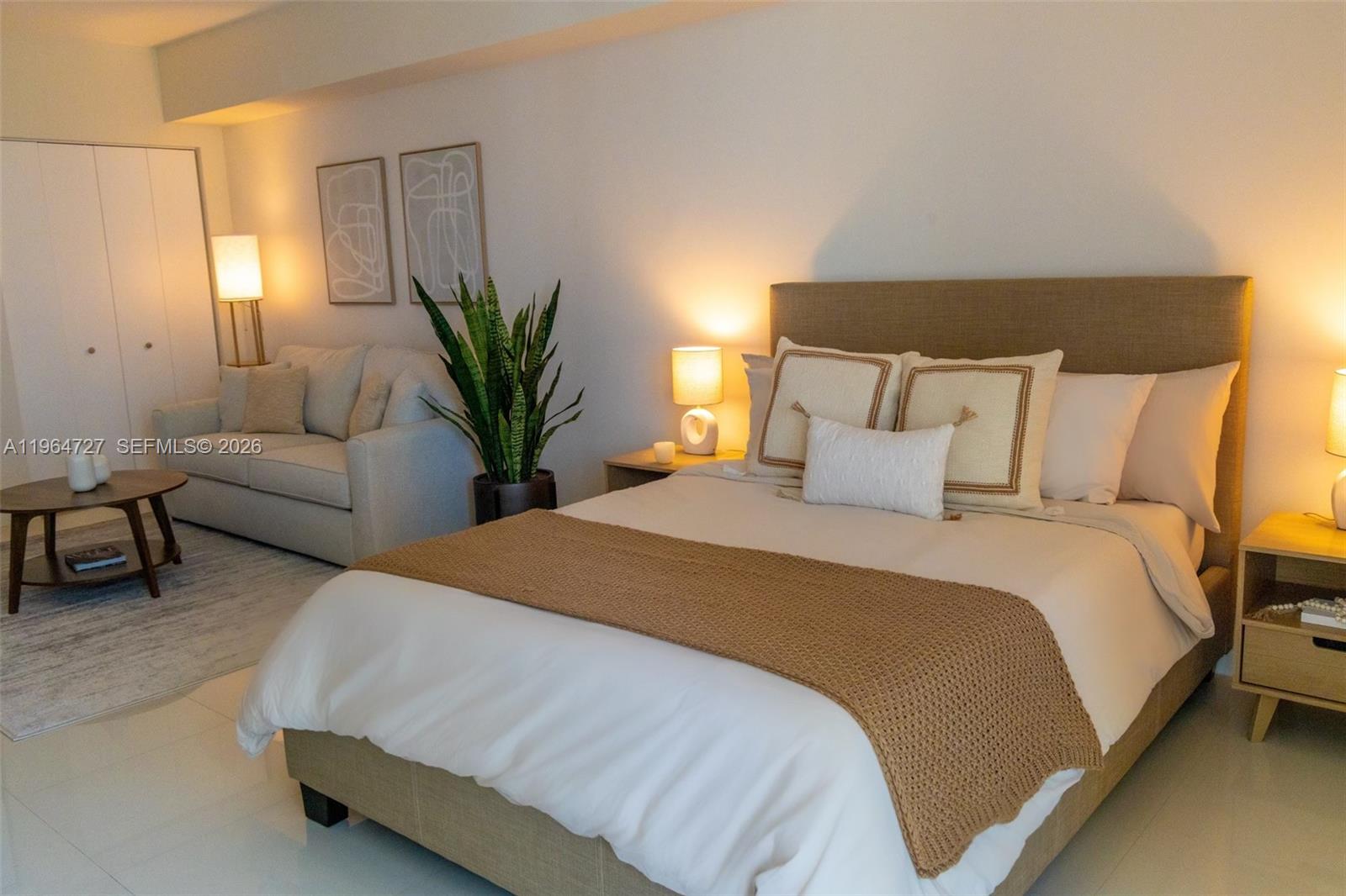 A bedroom features a bed with a tan headboard and a small adjacent seating area — 475 Brickell Ave # 3510, Miami FL 33131, MIAMI, FL