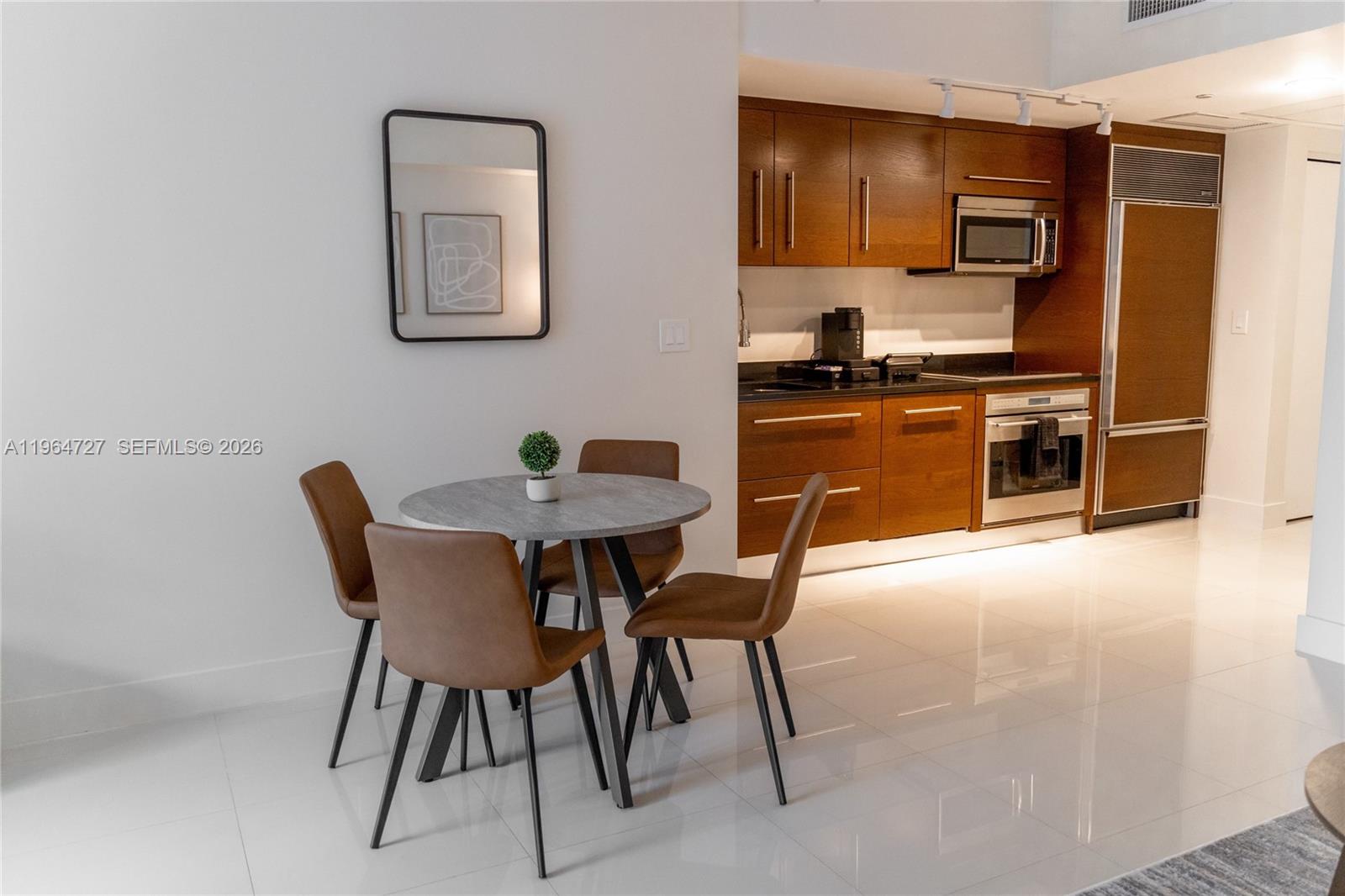 A dining area with a round table and four chairs sits beside a modern kitchen — 475 Brickell Ave # 3510, Miami FL 33131, MIAMI, FL
