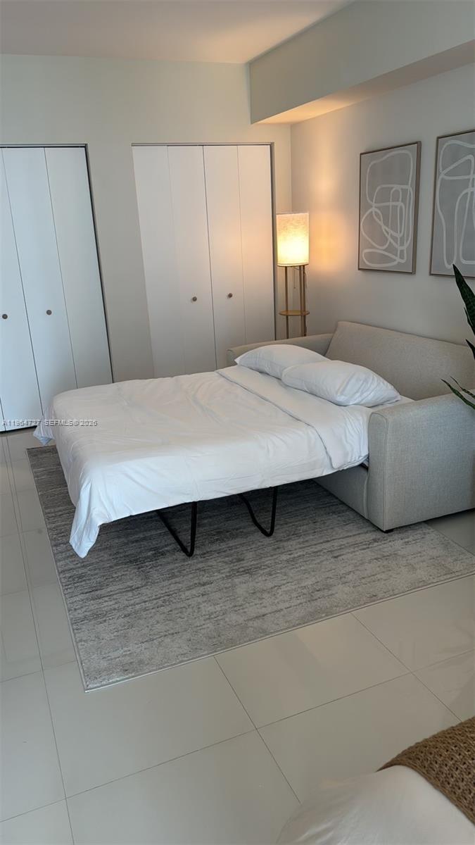 A bedroom features a pull-out sofa bed, a floor lamp, and two closets — 475 Brickell Ave # 3510, Miami FL 33131, MIAMI, FL