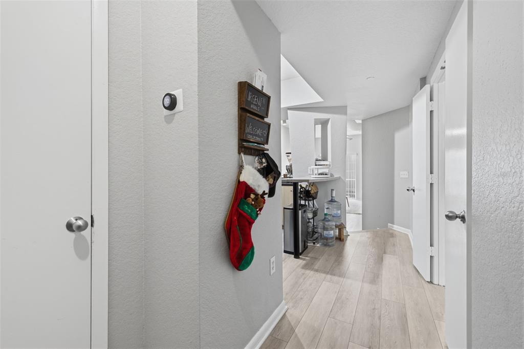 A hallway with light wood-look flooring leads toward a kitchen area with a water cooler — 520 S ARMENIA AVENUE UNIT 1239A, TAMPA, FL