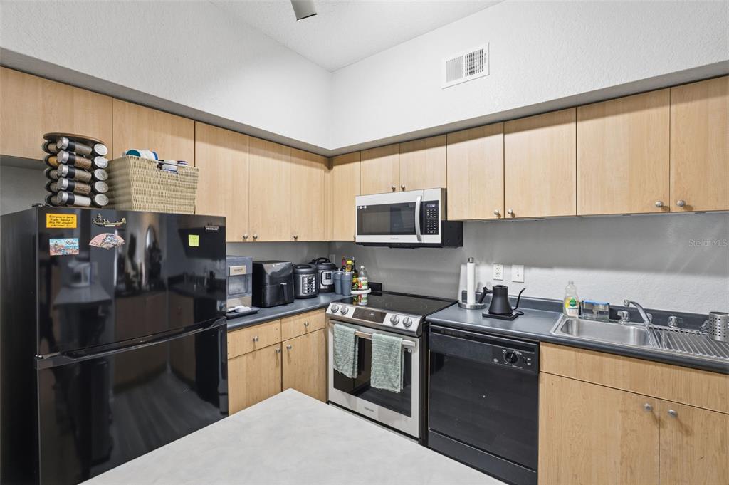 A kitchen features light wood cabinets, black appliances, and a gray countertop — 520 S ARMENIA AVENUE UNIT 1239A, TAMPA, FL