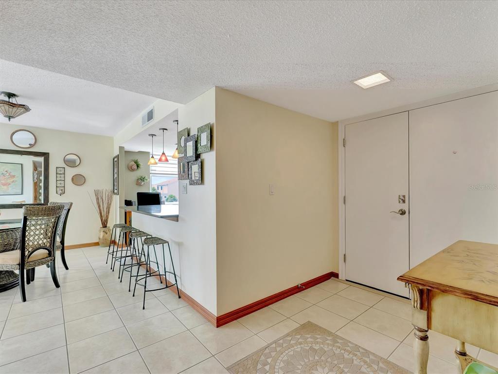 A tiled entryway leads to a dining area and a kitchen breakfast bar with stools — 1400 GULF BOULEVARD UNIT 204, CLEARWATER BEACH, FL