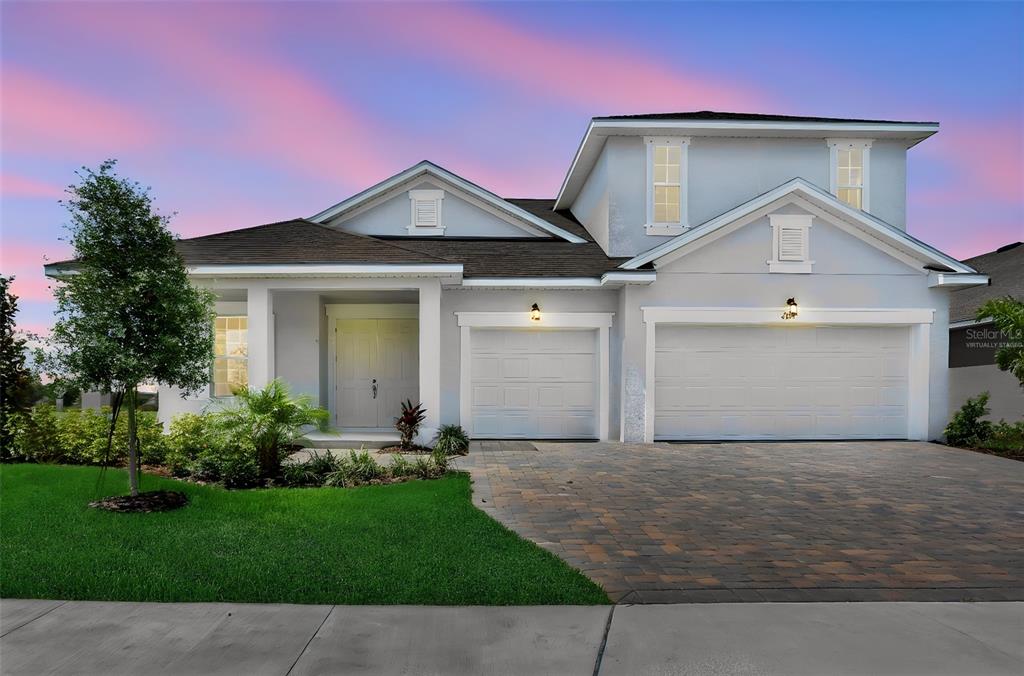 A two-story house with a paved driveway, three-car garage, and a light-colored exterior — 7414 SEA MANATEE STREET, PARRISH, FL