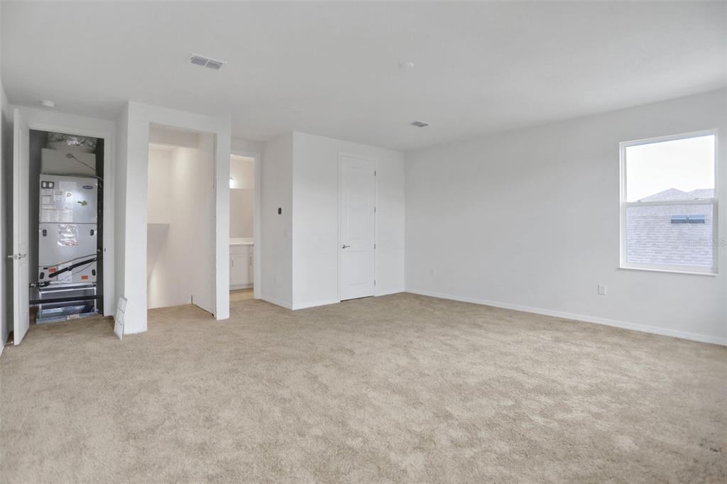 An empty carpeted room features a utility closet with an HVAC unit and a window — 7414 SEA MANATEE STREET, PARRISH, FL