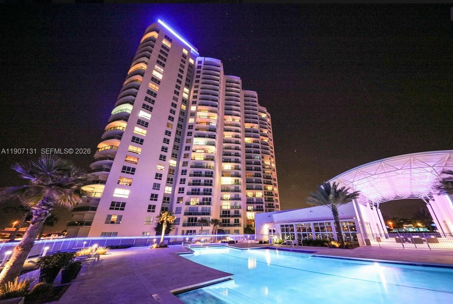 A swimming pool sits between two illuminated high-rise apartment buildings at night — 231 Riverside Dr # 510, Daytona FL 32117, DAYTONA, FL