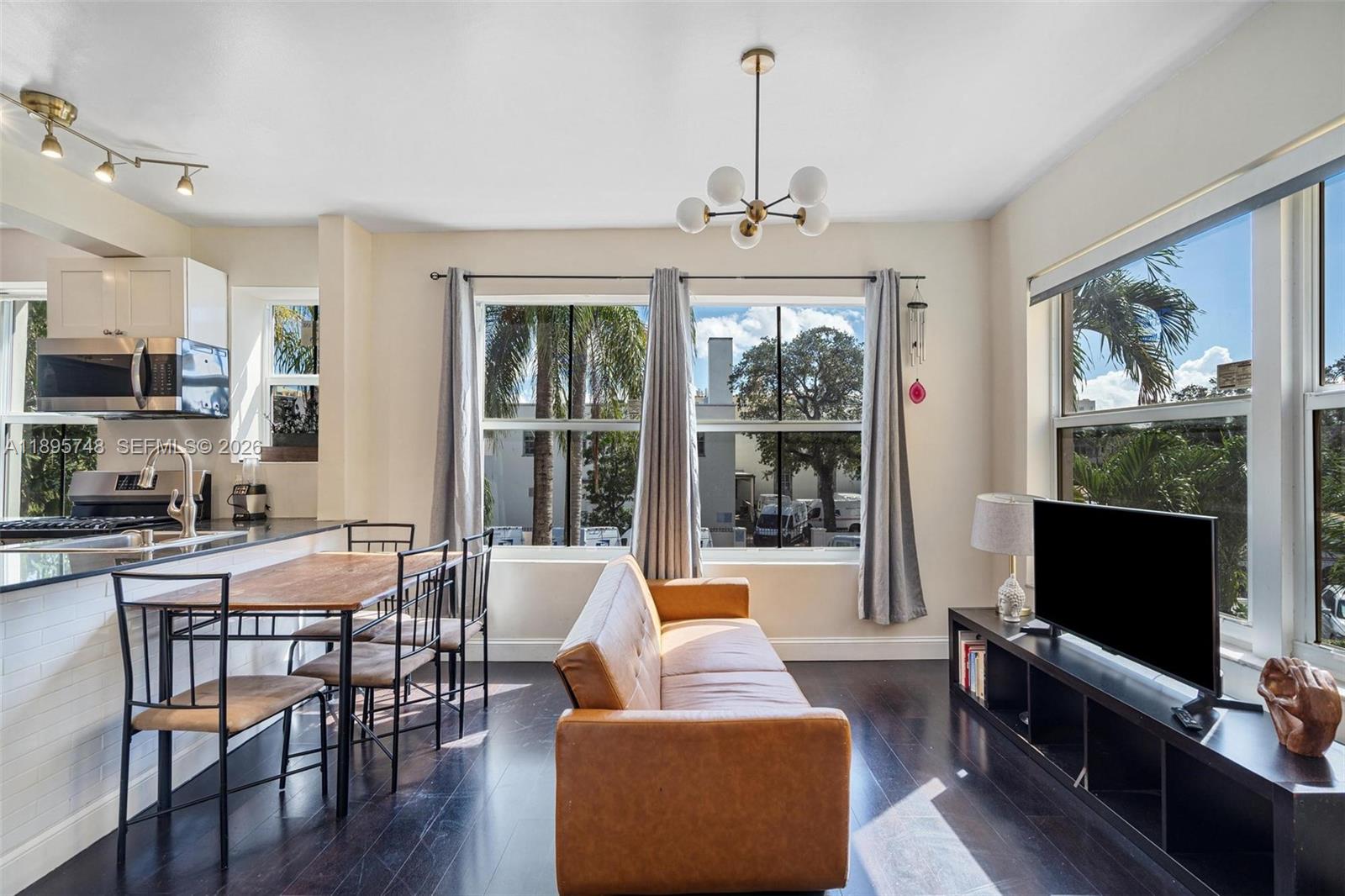 A living room and dining area feature dark wood floors, a leather sofa, and windows — 1320 Drexel Ave # 200, Miami Beach FL 33139, MIAMI BEACH, FL