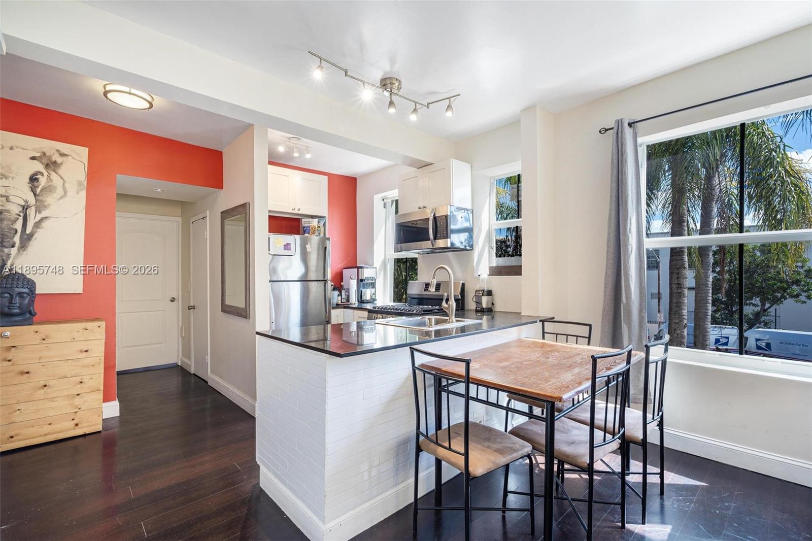 A kitchen with a breakfast bar, dark wood floors, and a dining table — 1320 Drexel Ave # 200, Miami Beach FL 33139, MIAMI BEACH, FL