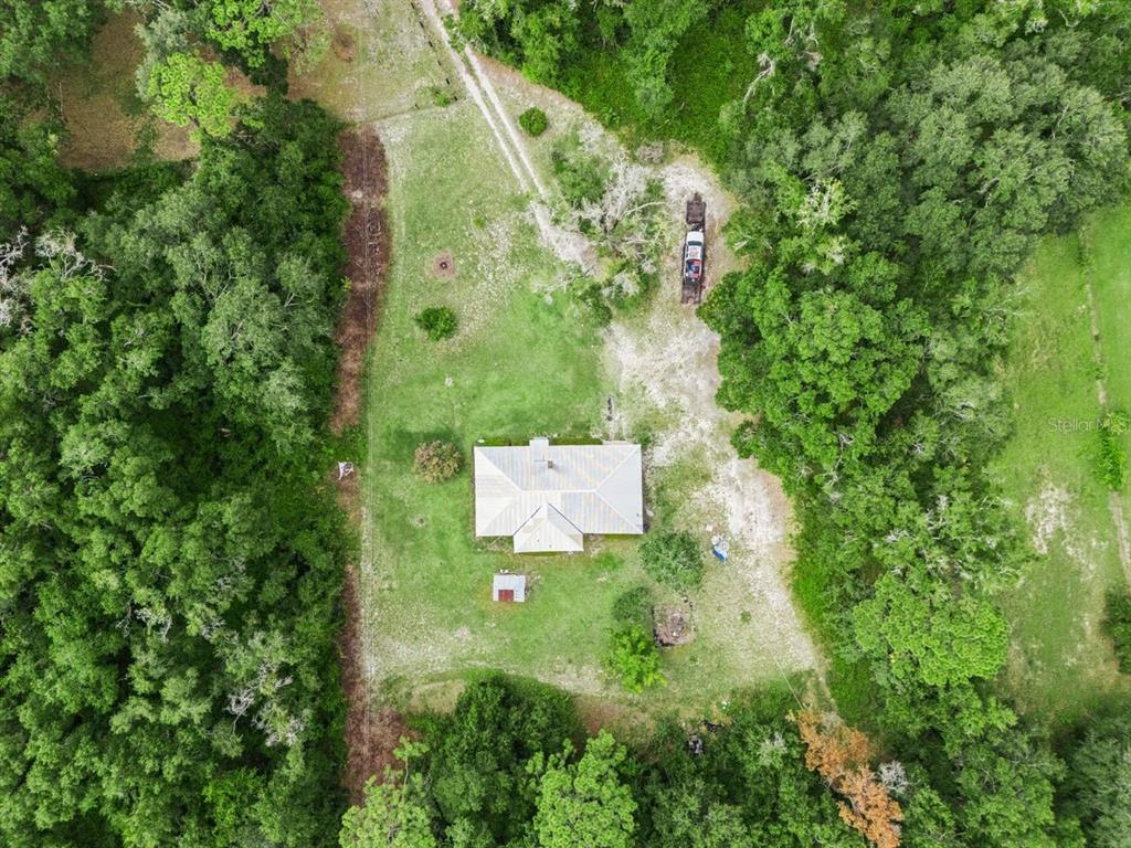 An aerial view shows a house surrounded by a large grassy yard and dense woods — 6184 NE 54TH BOULEVARD, WILDWOOD, FL