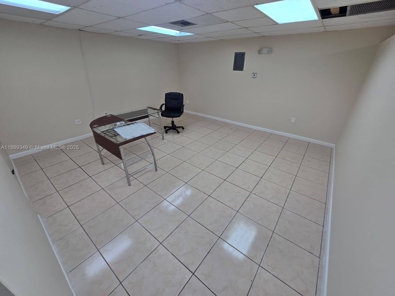 An empty office room features beige walls, tiled flooring, a glass desk, and a chair — 2501 N State Road 7 # 208, Margate FL 33063, MARGATE, FL
