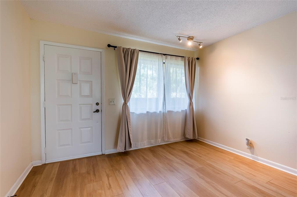 A room with light wood-look flooring, a white paneled door, and a window with curtains — 3062 EASTLAND BOULEVARD UNIT 406, CLEARWATER, FL
