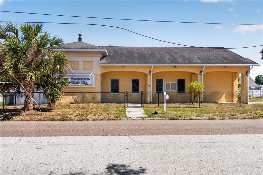 A yellow, single-story church building with a dark roof sits behind a chain-link fence — 2018 GRANT STREET, TAMPA, FL