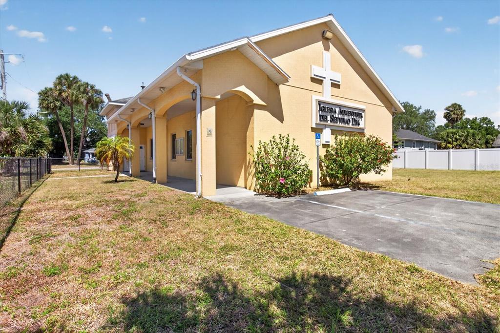 A yellow stucco church building features a covered entrance and a small paved parking area — 2018 GRANT STREET, TAMPA, FL