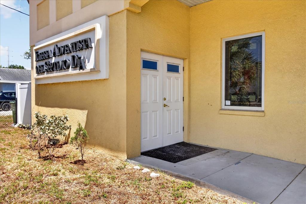 The exterior of a yellow building features a double door entrance and a church sign — 2018 GRANT STREET, TAMPA, FL