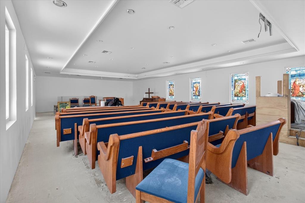 An interior view of a church sanctuary featuring rows of wooden pews and stained-glass windows — 2018 GRANT STREET, TAMPA, FL