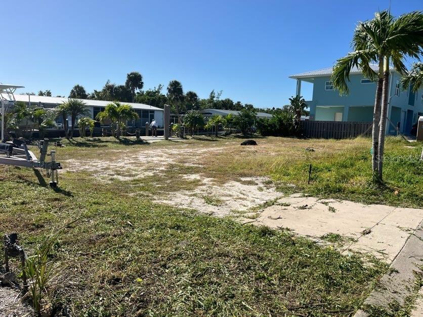 A vacant, grassy lot with a boat trailer and nearby houses under a clear sky — 766 SAINT JUDES DRIVE N, LONGBOAT KEY, FL