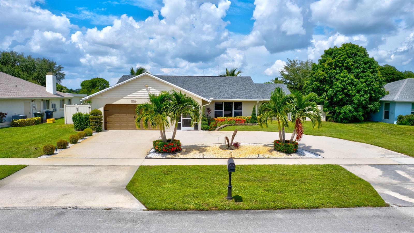 A single-story house with a two-car garage, palm trees, and a landscaped front yard — 1104 Jackpine Street, Wellington FL 33414, WELLINGTON, FL
