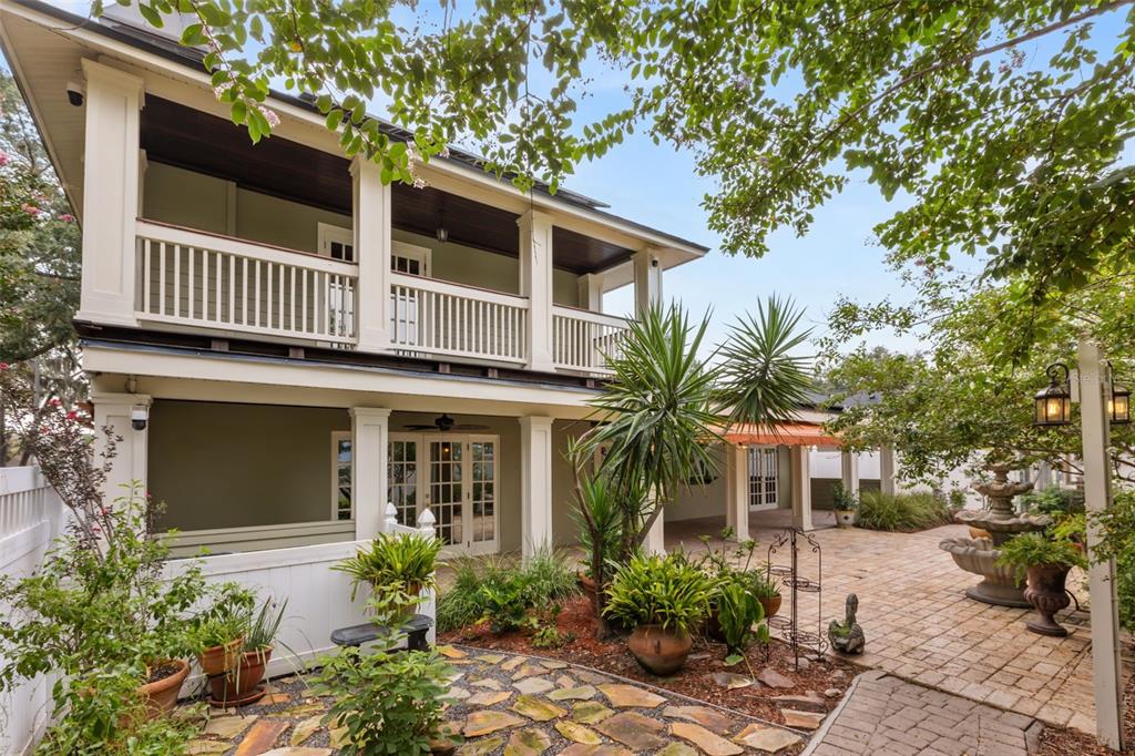 A two-story house with a balcony and patio overlooks a landscaped garden with a fountain — 900 LENMORE COURT, ORLANDO, FL
