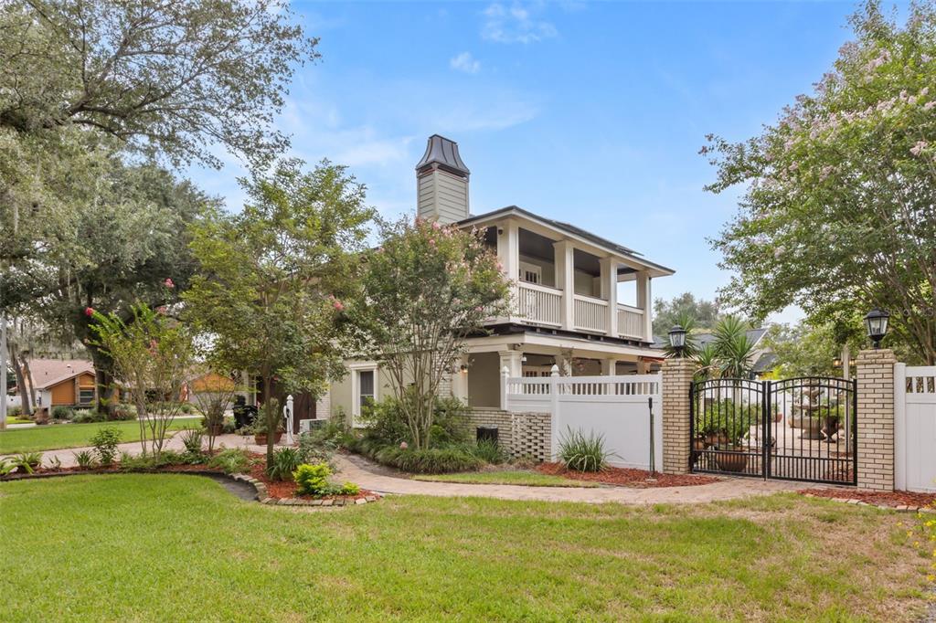 A two-story house with a wrap-around porch, balcony, and a gated brick entrance — 900 LENMORE COURT, ORLANDO, FL