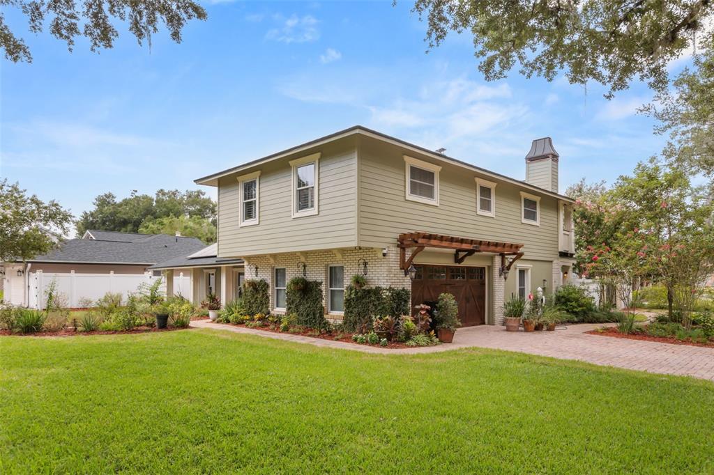 A two-story house with light green siding, a brick lower level, and a wooden pergola — 900 LENMORE COURT, ORLANDO, FL