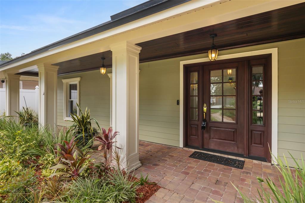 A covered front porch with a brick floor, white columns, and a dark wood door — 900 LENMORE COURT, ORLANDO, FL