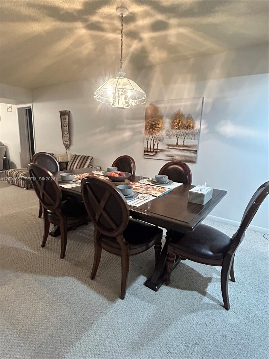 A dining room features a dark wood table with six chairs under a pendant light — 1701 Whitehall Dr # 403, Davie FL 33324, DAVIE, FL