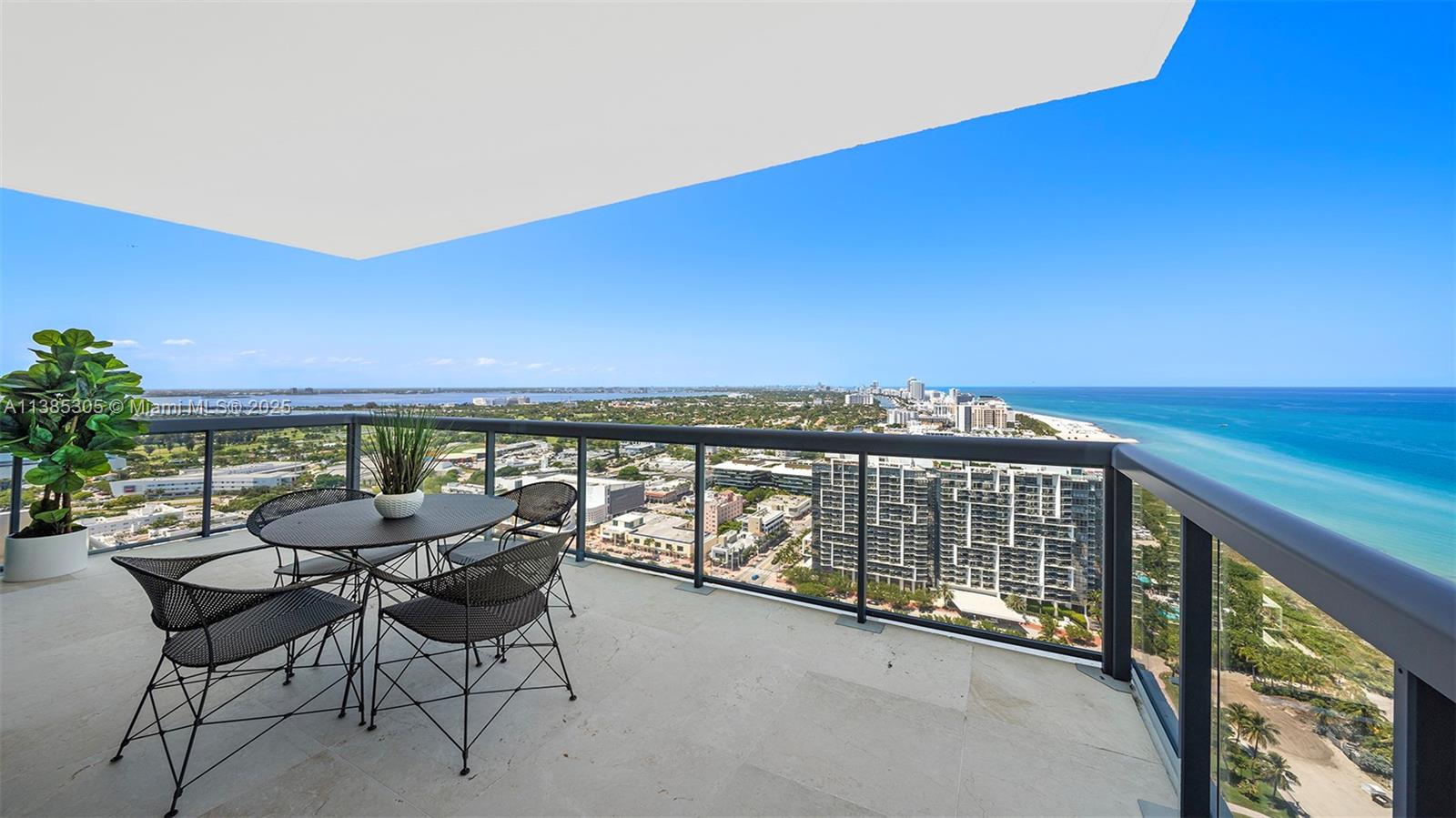 A high-rise balcony features a dining set, a potted plant, and expansive ocean views — 101 20th St # 3903, Miami Beach FL 33139, MIAMI BEACH, FL