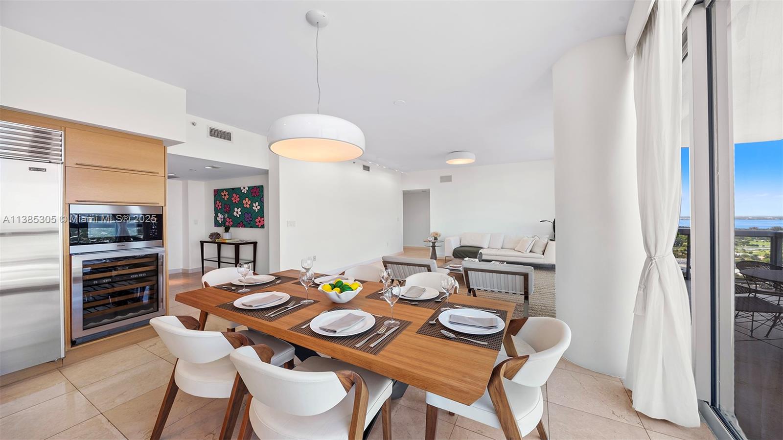 A dining area with a wooden table and white chairs sits before a living room — 101 20th St # 3903, Miami Beach FL 33139, MIAMI BEACH, FL