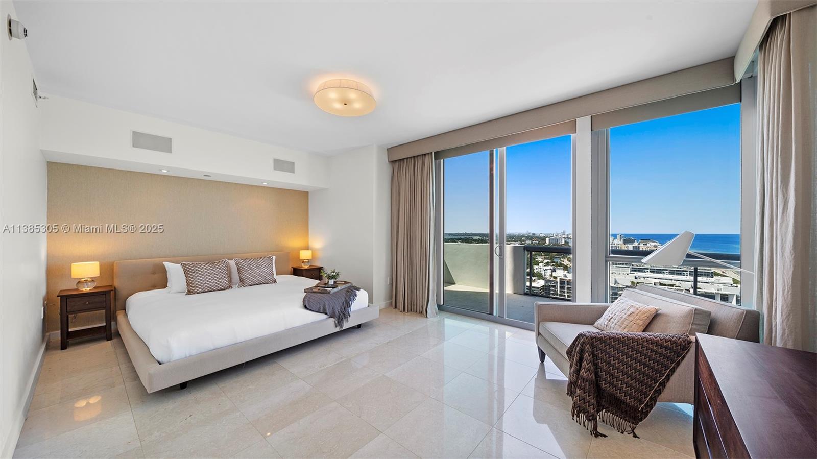 A modern bedroom features a king bed, tile floors, and floor-to-ceiling windows with ocean views — 101 20th St # 3903, Miami Beach FL 33139, MIAMI BEACH, FL